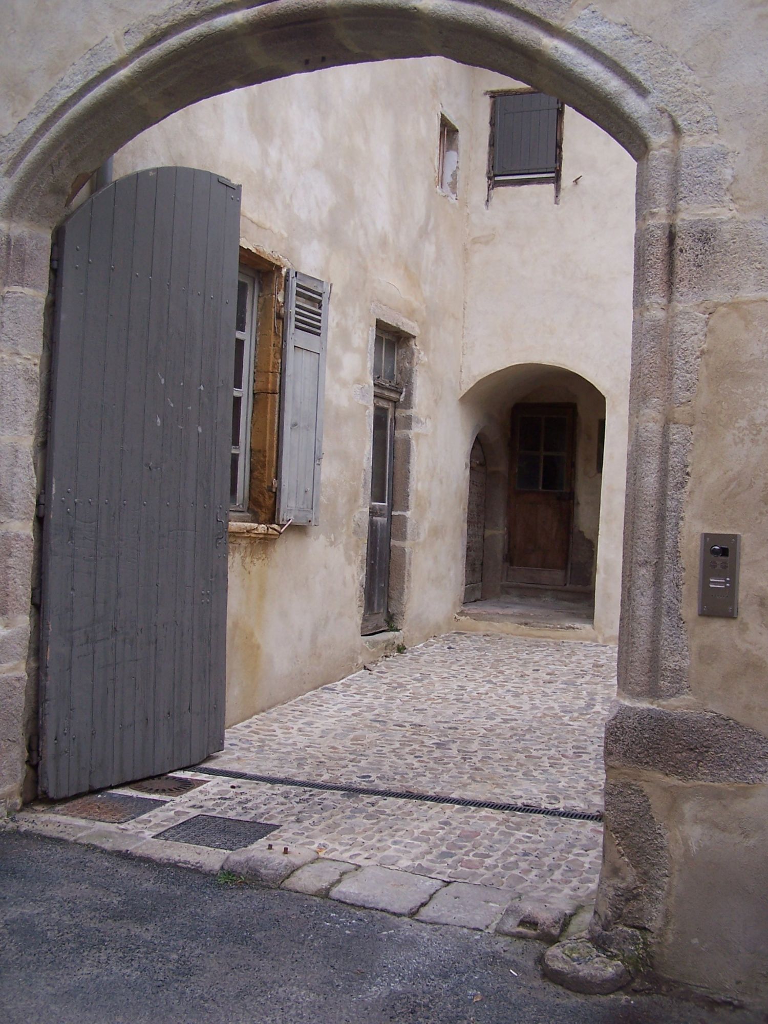 Porche en pierre de la maison Gonnard, rue des Grés, ouvrant sur une cour pavée